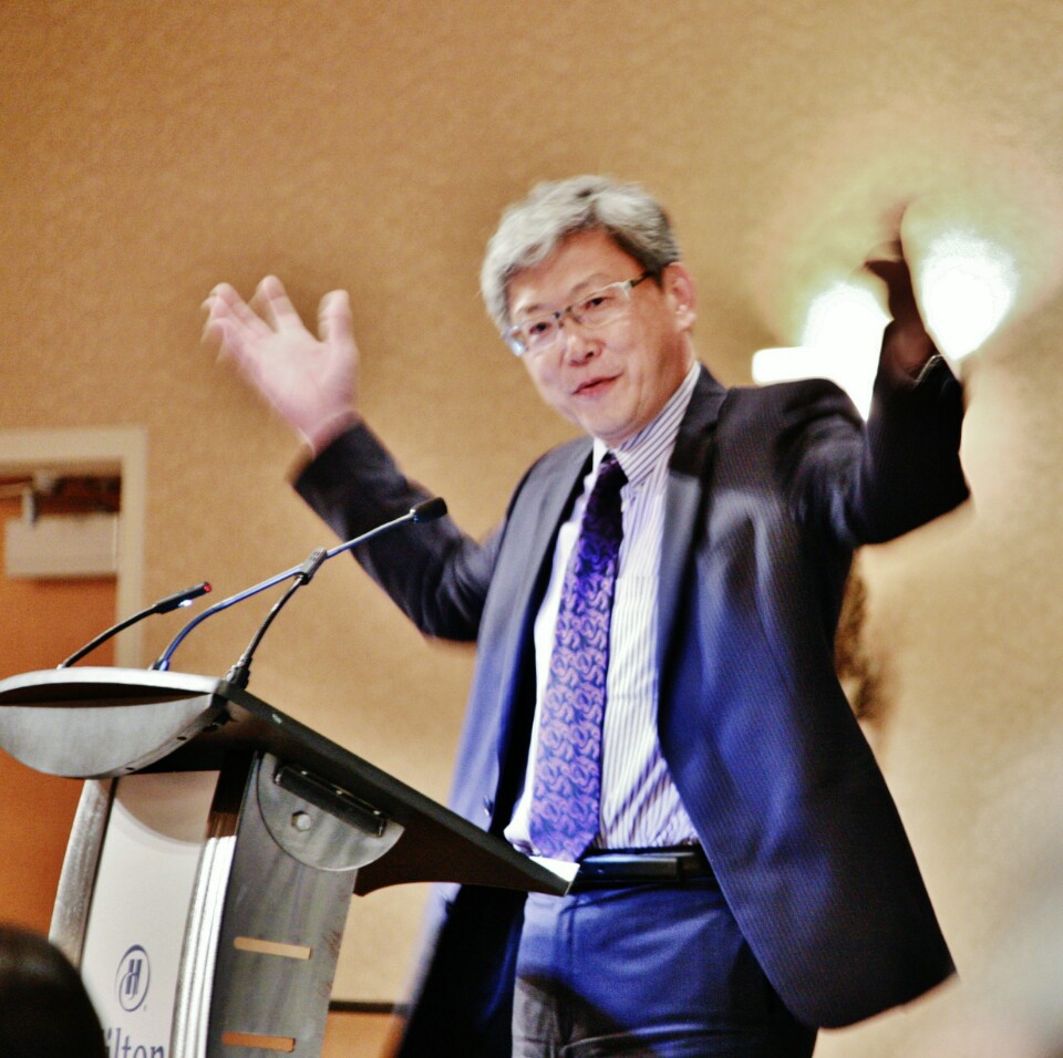 Michael Hwang gesturing with both hands while speaking at a lectern